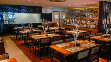 A restaurant with multiple tables, chairs, and a bar area with shelves of bottles.