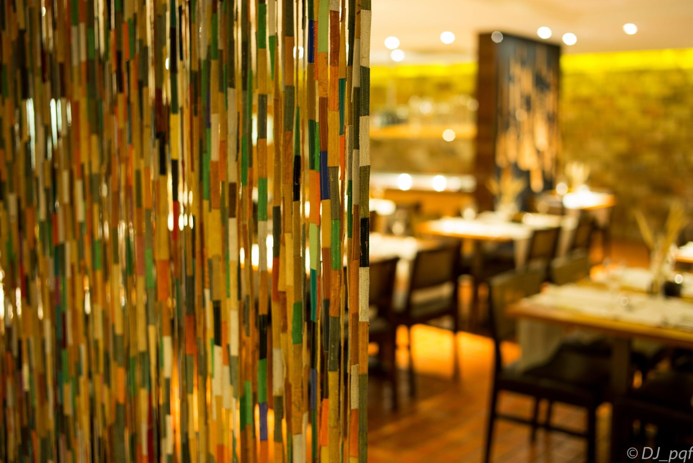 Interior de un restaurante con decoración mural abstracta y colorida, y un comedor con mesas y sillas.