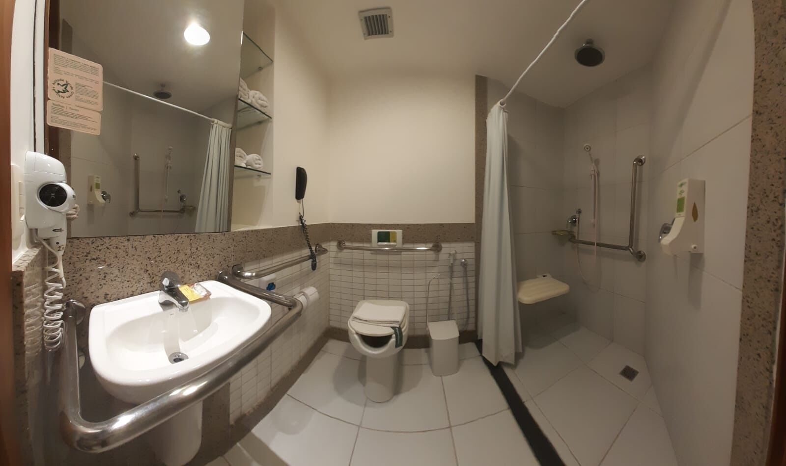 A bathroom with a sink, toilet, shower, and hand dryer.