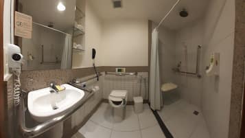 A bathroom with a sink, toilet, shower, and hand dryer.