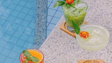Three cocktails on a poolside table with a pool in the background.