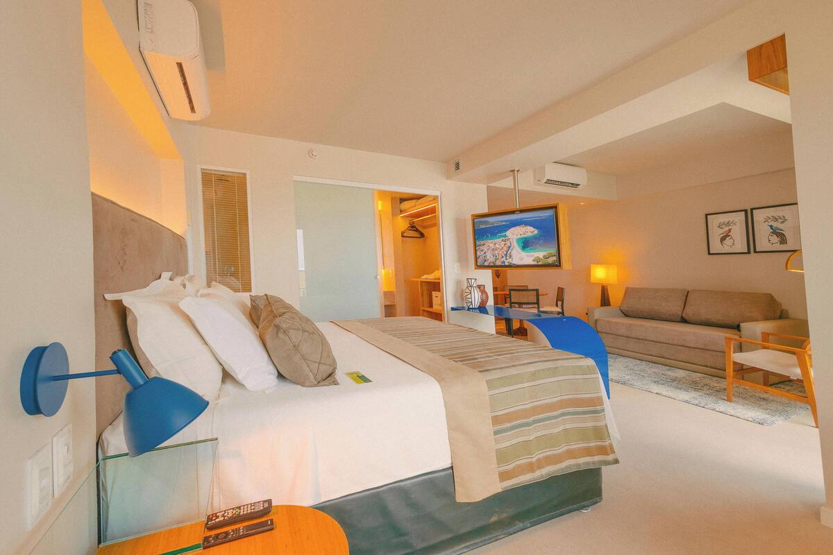 Una habitación de hotel moderna con cama, sofá, televisión y escritorio.