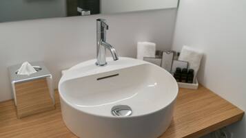 A white sink with a modern faucet, a tissue box, and a soap dispenser on a wooden countertop.