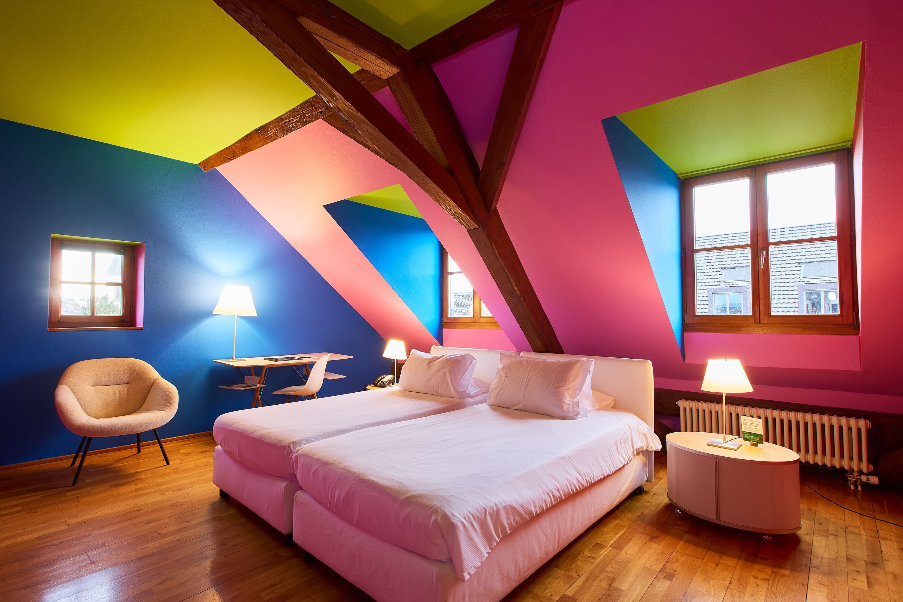 A bedroom with a large bed, a chair, a table, and a lamp.