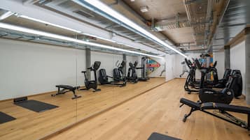 A gym with exercise equipment, wooden floors, and mirrored walls.