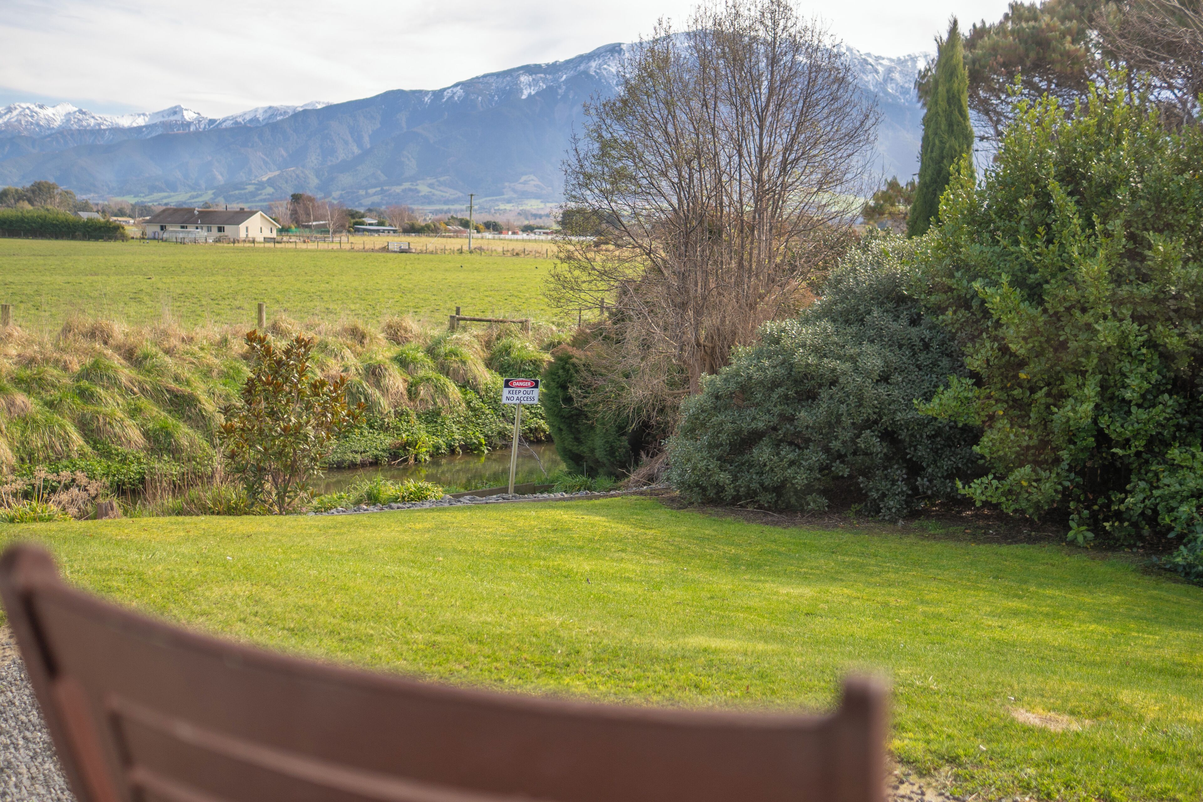 Un banco con vistas a un campo verde, con una cadena montañosa al fondo.