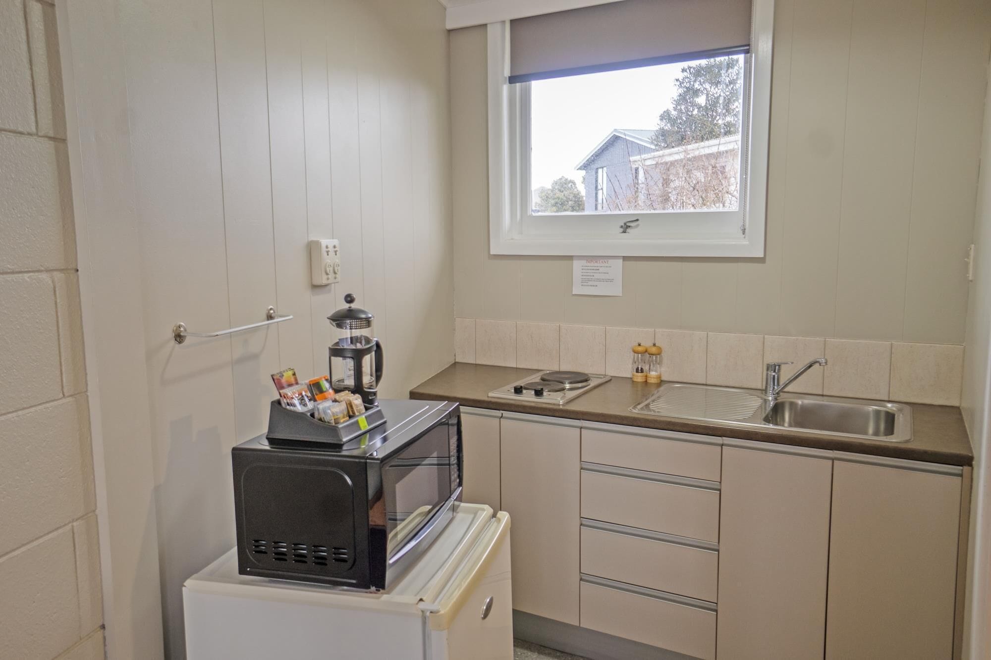 A compact kitchenette with a microwave, coffee maker, and sink.