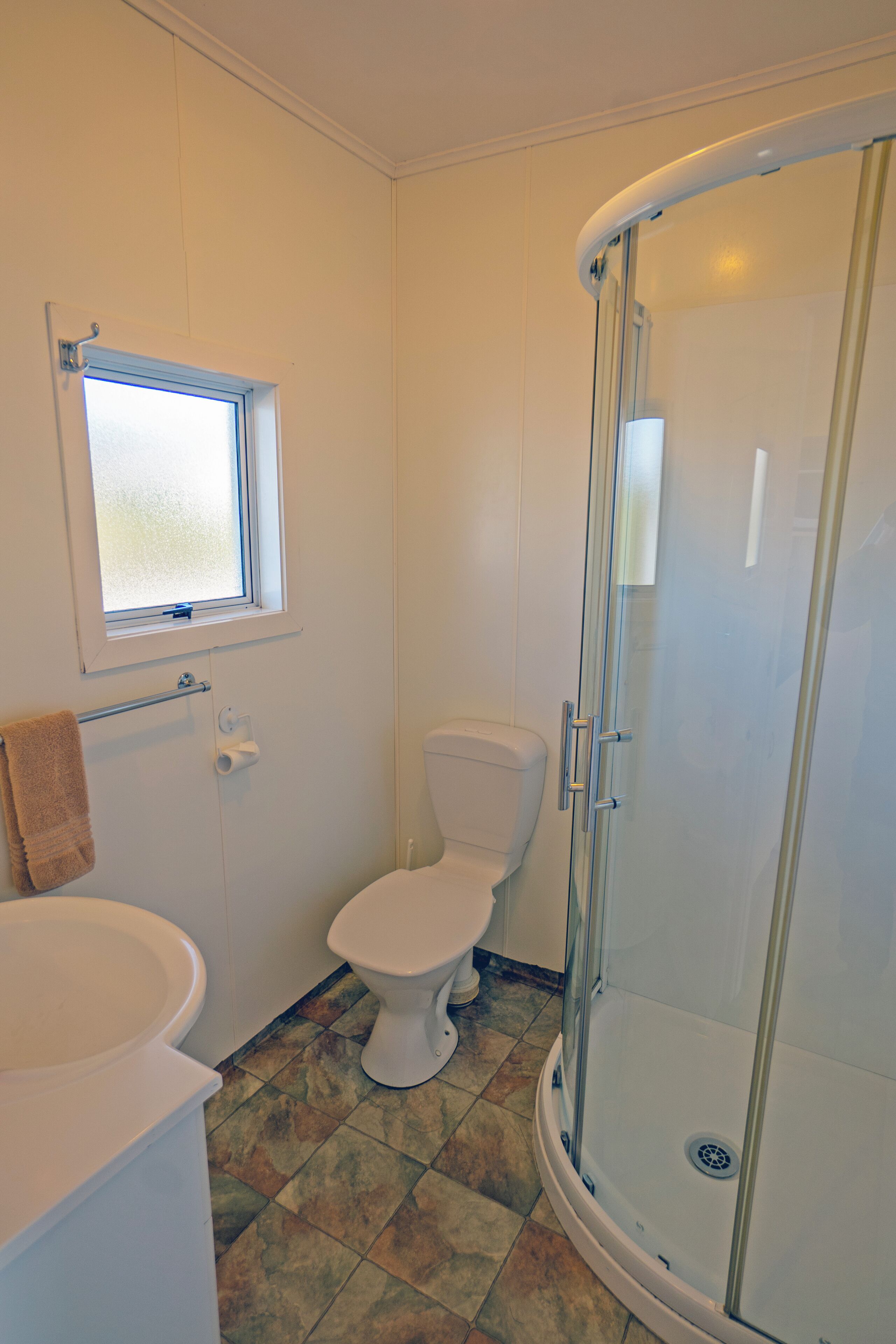 A bathroom with a toilet, a shower enclosure, and a window.