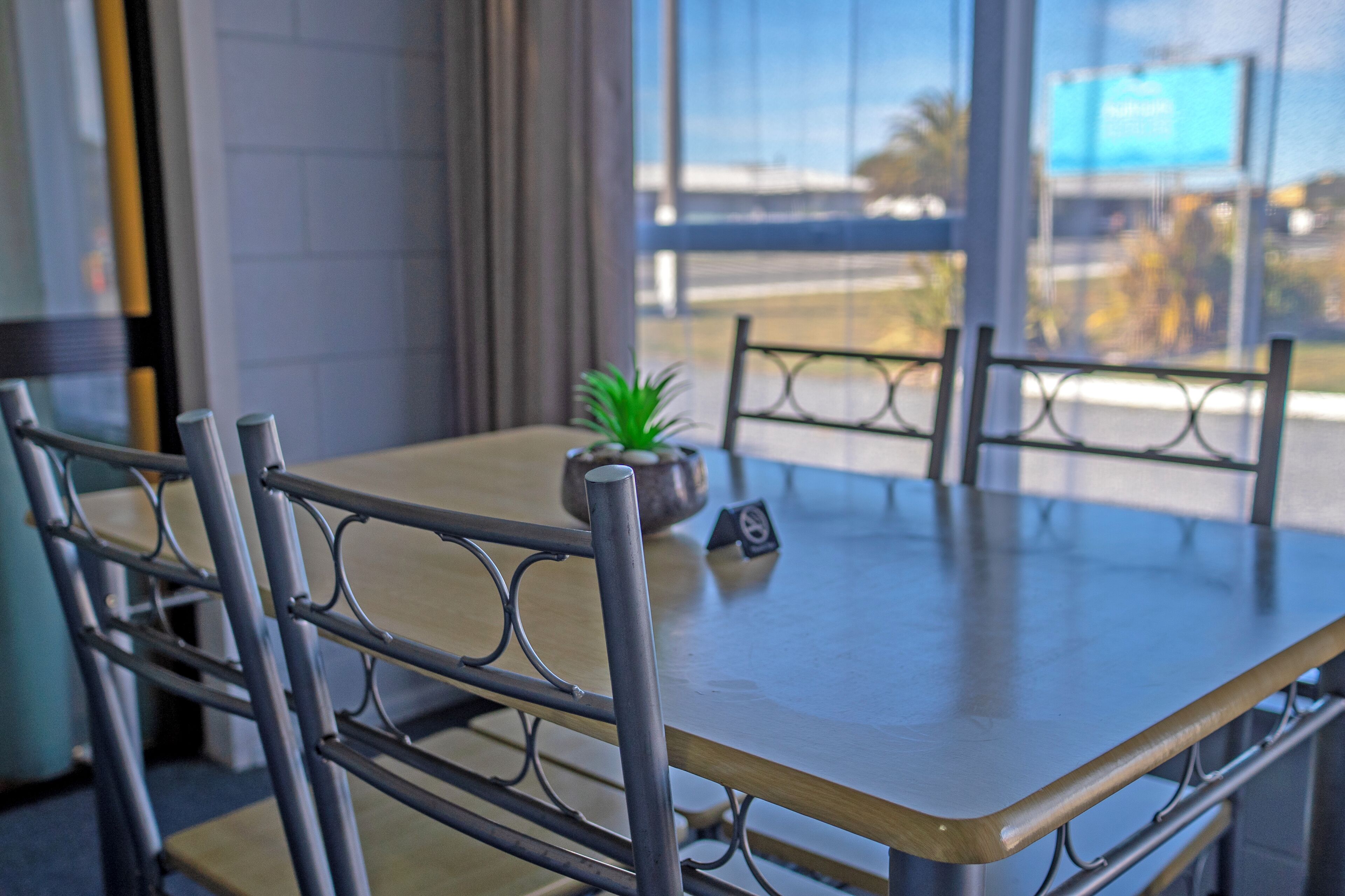 A dining table with metal chairs, a small potted plant, and a menu stand.