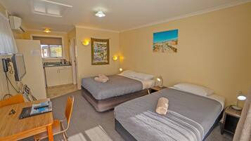 A hotel room with two beds, a desk, and a kitchenette.