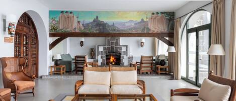 Un salón amplio con chimenea, asientos cómodos y un mural grande en la pared.