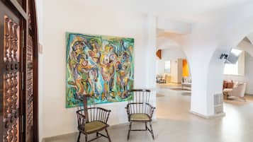 Un vestíbul ampli amb dues cadires de fusta, un quadre abstracte gran i un disseny interior modern.
