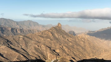 Un paisaje montañoso con un pico rocoso destacado y un pequeño asentamiento a su base.