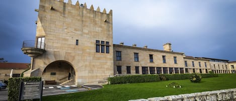 A historic building with a prominent tower, a covered entrance, and a well-maintained lawn.