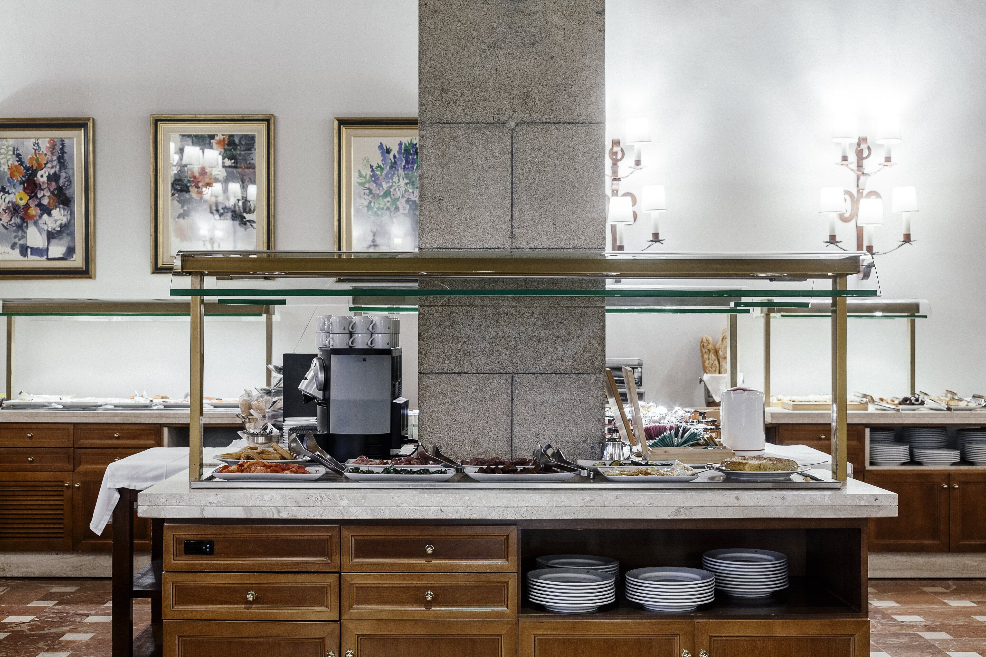A buffet setup with various food items, a coffee machine, and a stack of plates.