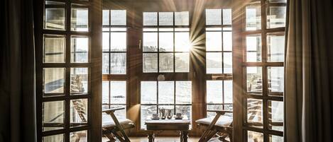 A room with a large window, wooden rocking chairs, and a small table with a pitcher and cups.