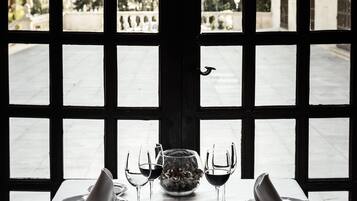 Mesa para dos con vistas a un patio a través de una ventana con diseño de cuadrícula.