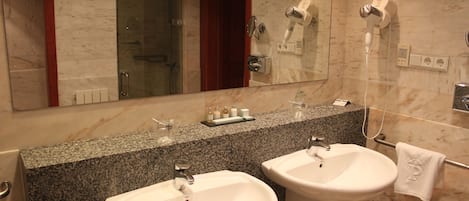 A bathroom with two sinks, a mirror, and a shower.
