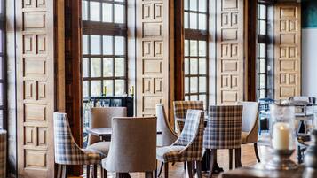 A restaurant interior with wooden paneled walls, plaid-patterned chairs, and a candle on a table.