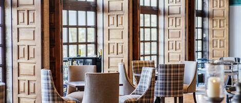 A restaurant interior with wooden paneled walls, plaid-patterned chairs, and a candle on a table.