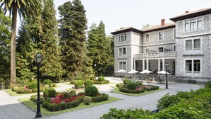 Un patio con un edificio de piedra, rodeado de jardines y árboles bien cuidados.