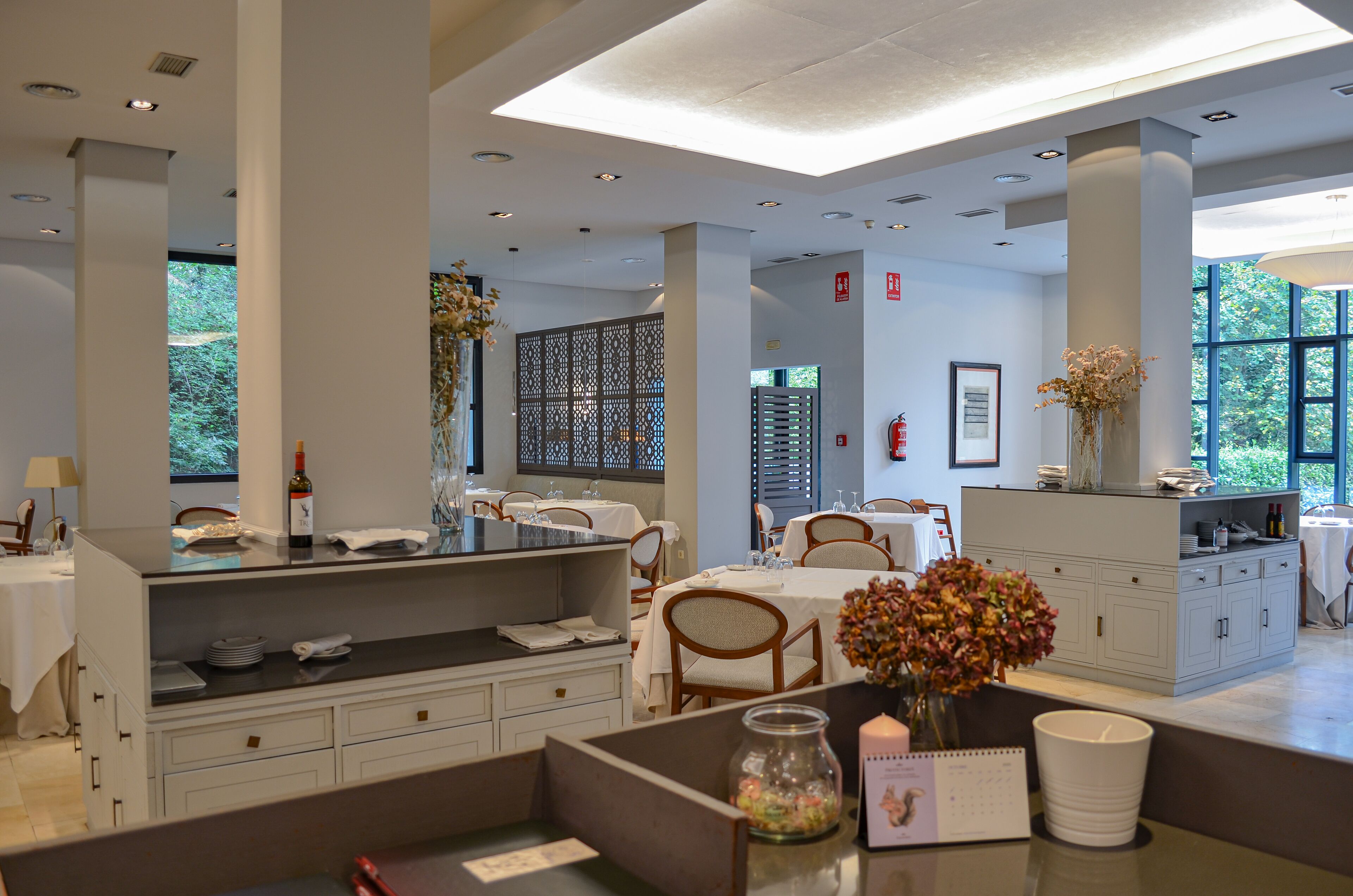 A modern hotel lobby with a reception desk, seating area, and large windows offering natural light.