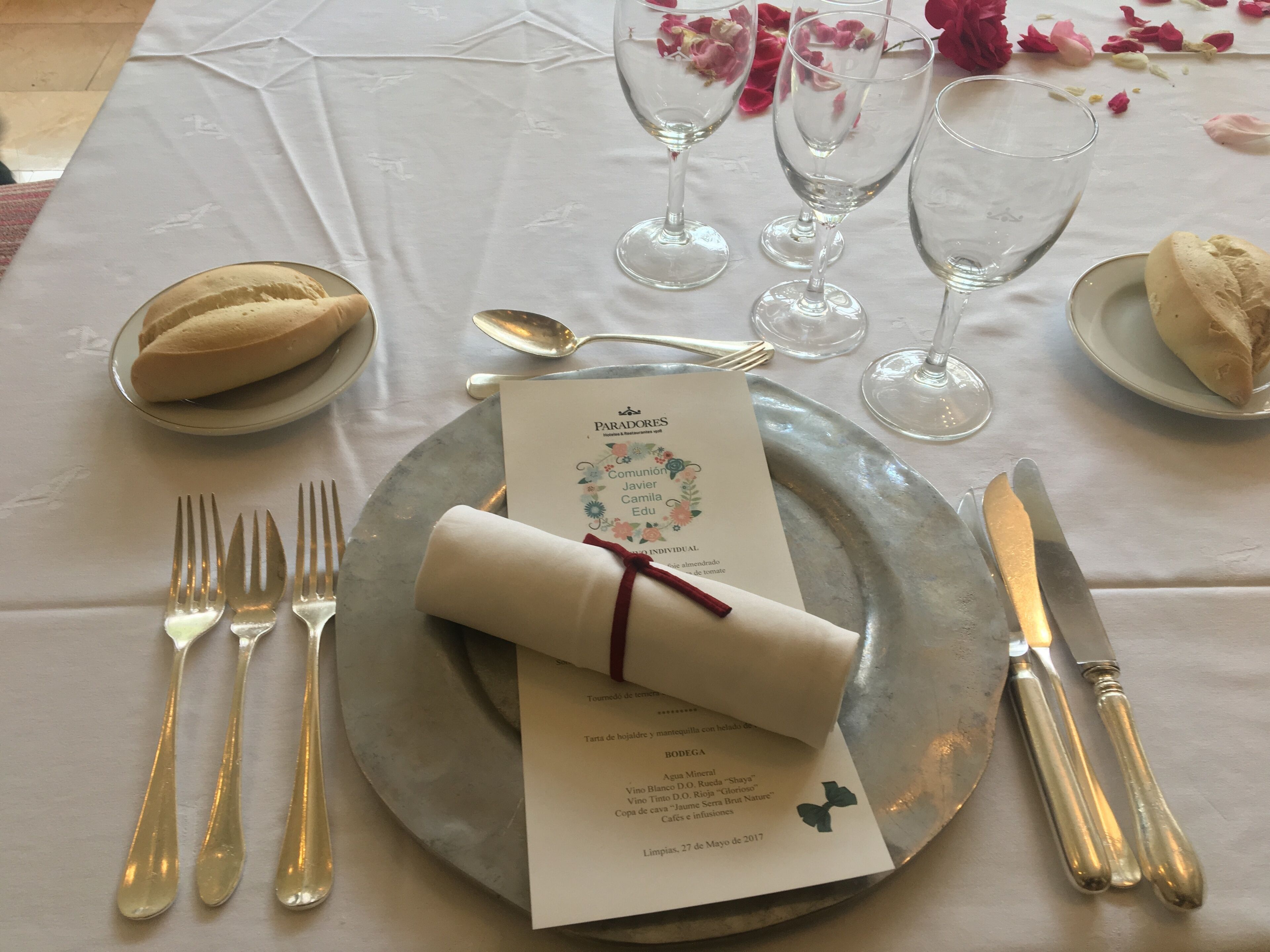 Una mesa lista para comer, con un menú, cubiertos y vasos.