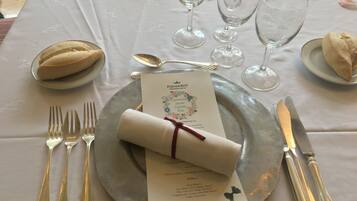 Una mesa lista para comer, con un menú, cubiertos y vasos.