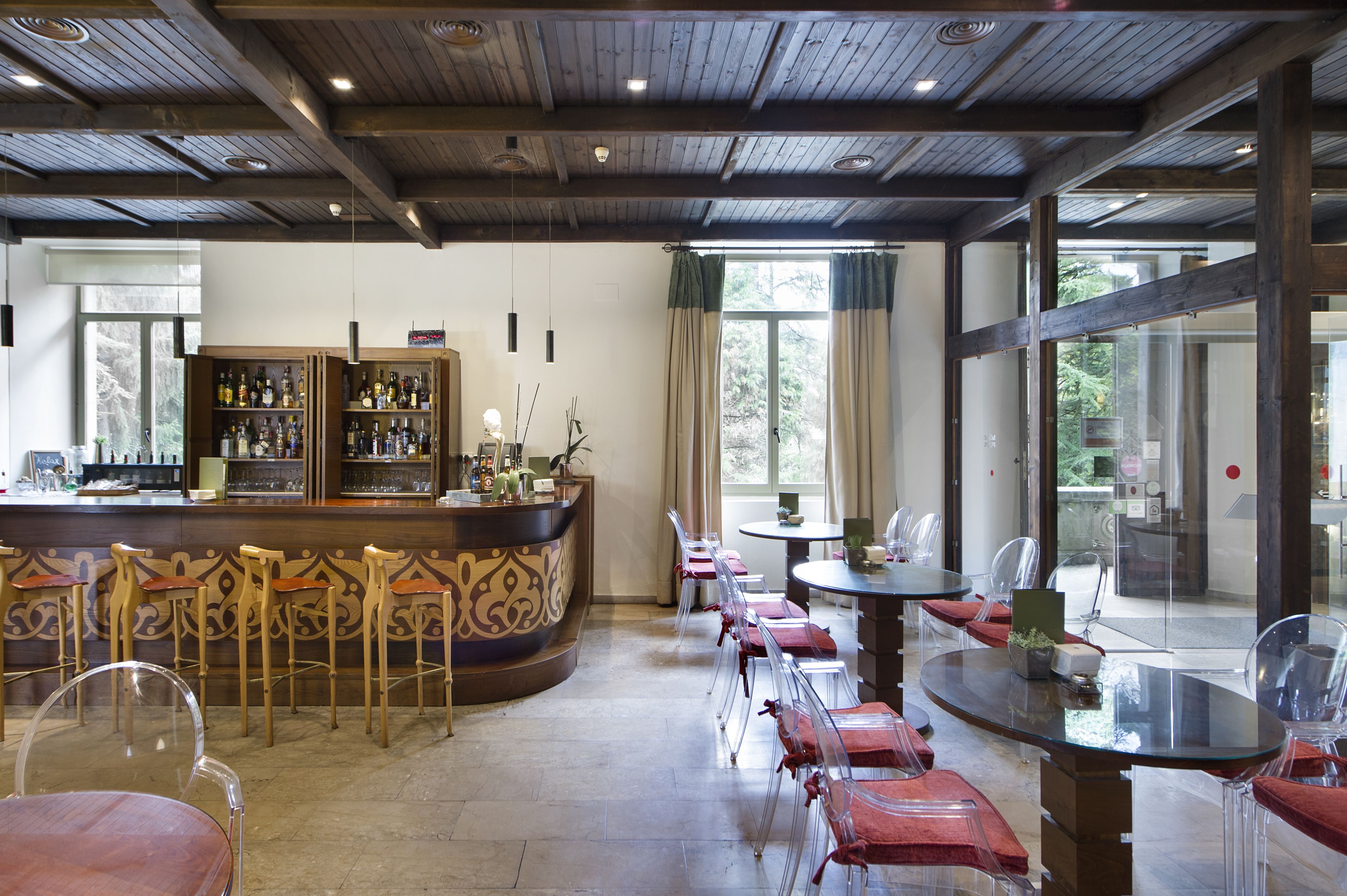 Eine Bar mit Holztresen, Barhocker und einer Sitzgelegenheit mit runden Tischen und Stühlen.