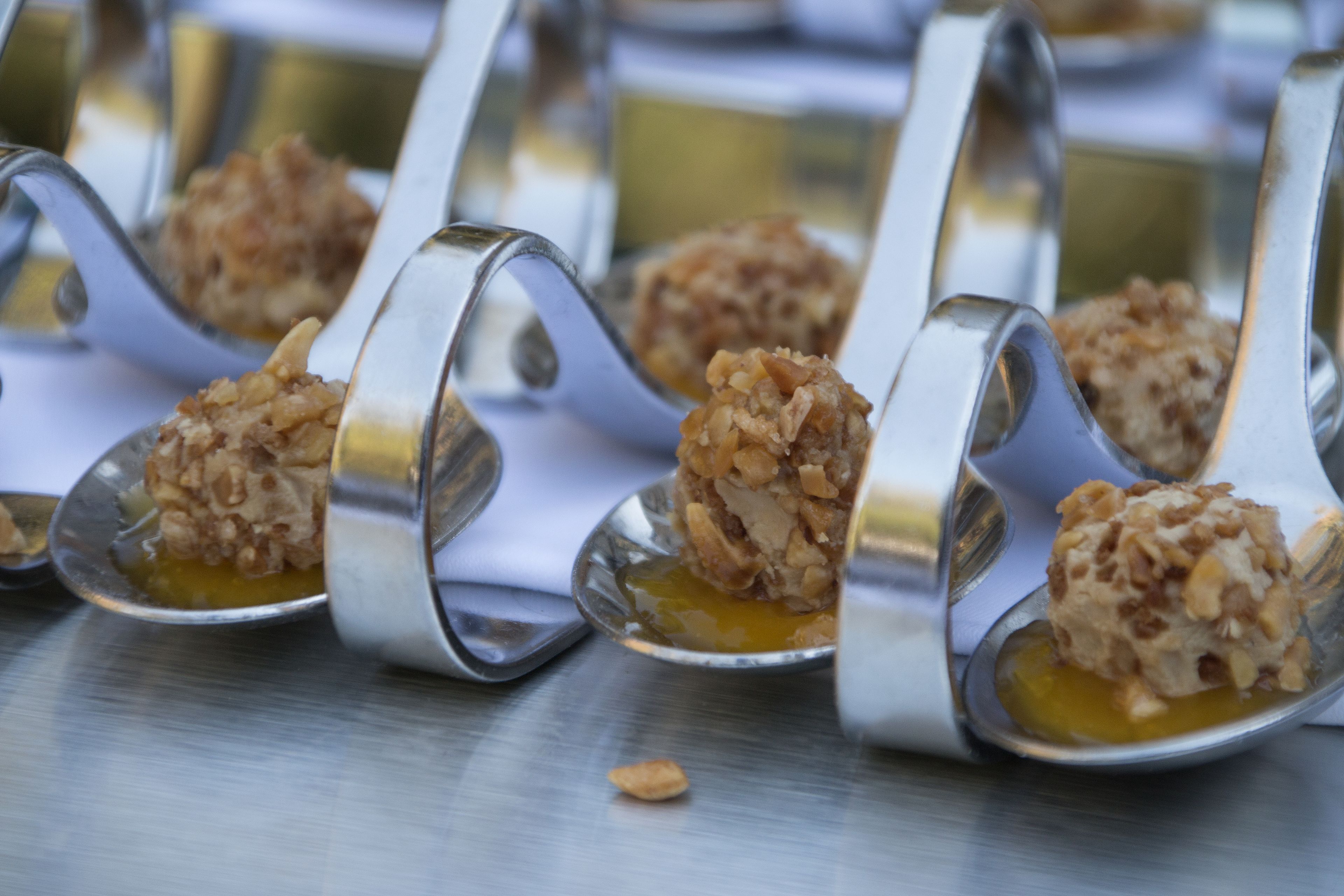 A row of spoons with desserts on them.