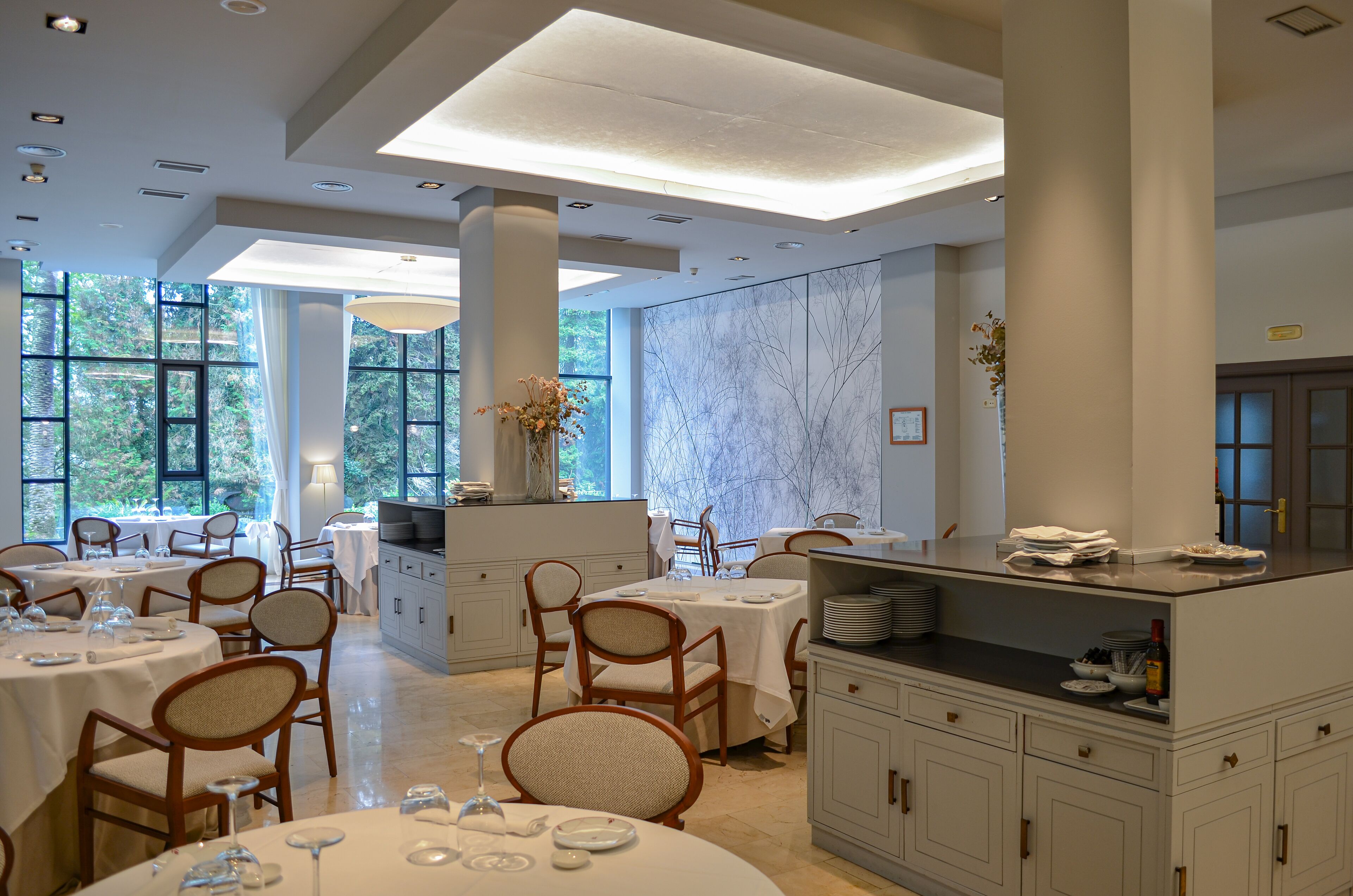 A dining area with round tables, chairs, and a buffet counter.