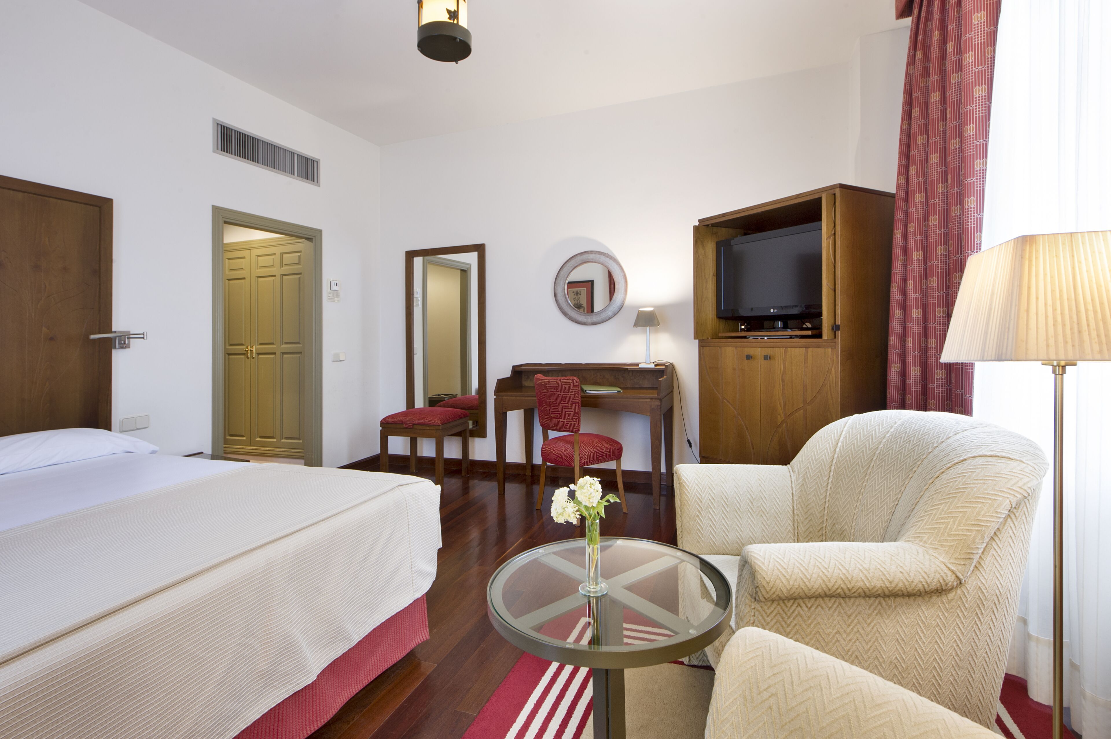 Una habitación de hotel con una cama, un escritorio con una silla, un televisor y una lámpara.