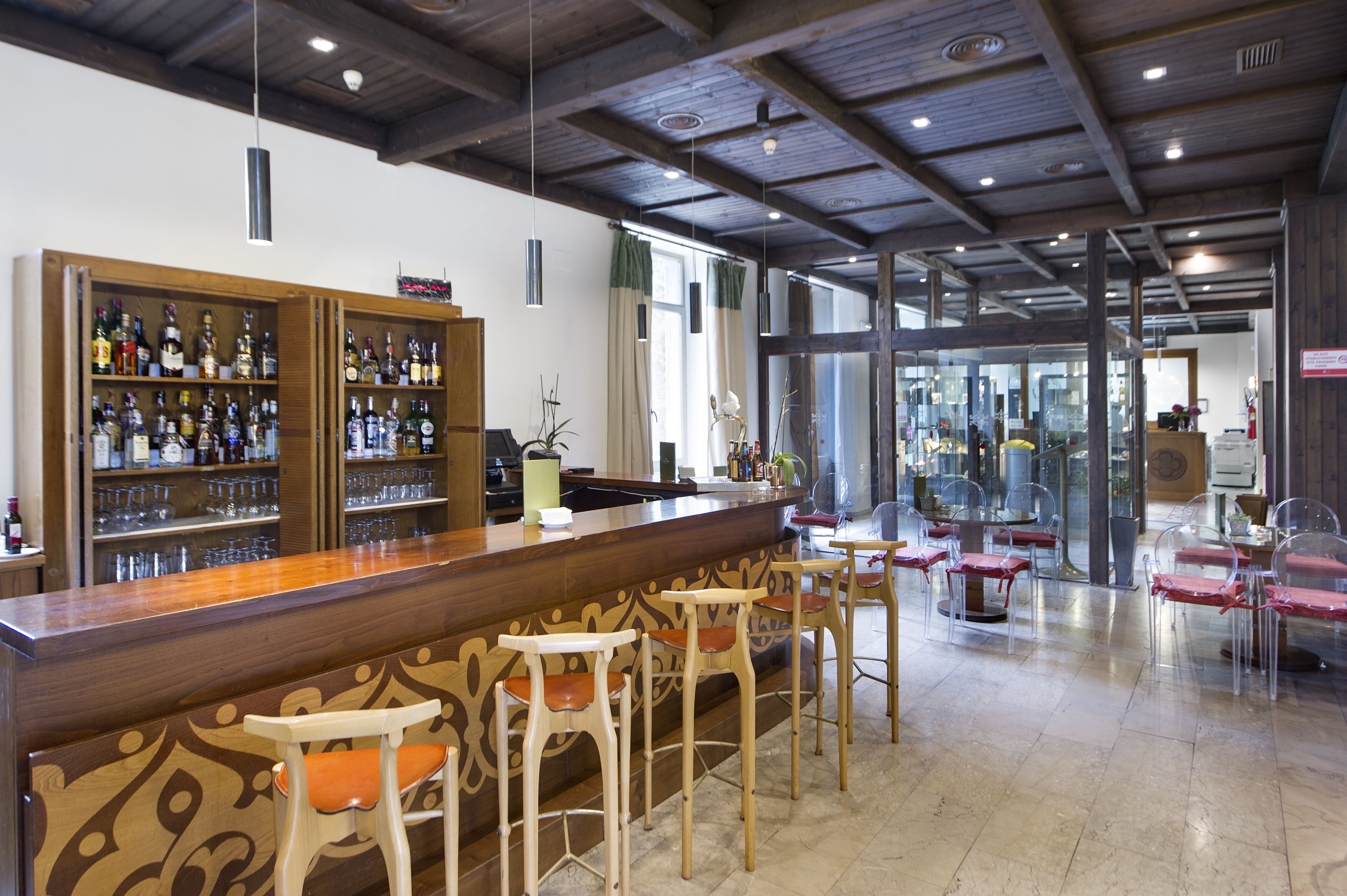 A bar area with wooden bar stools and shelves stocked with bottles.