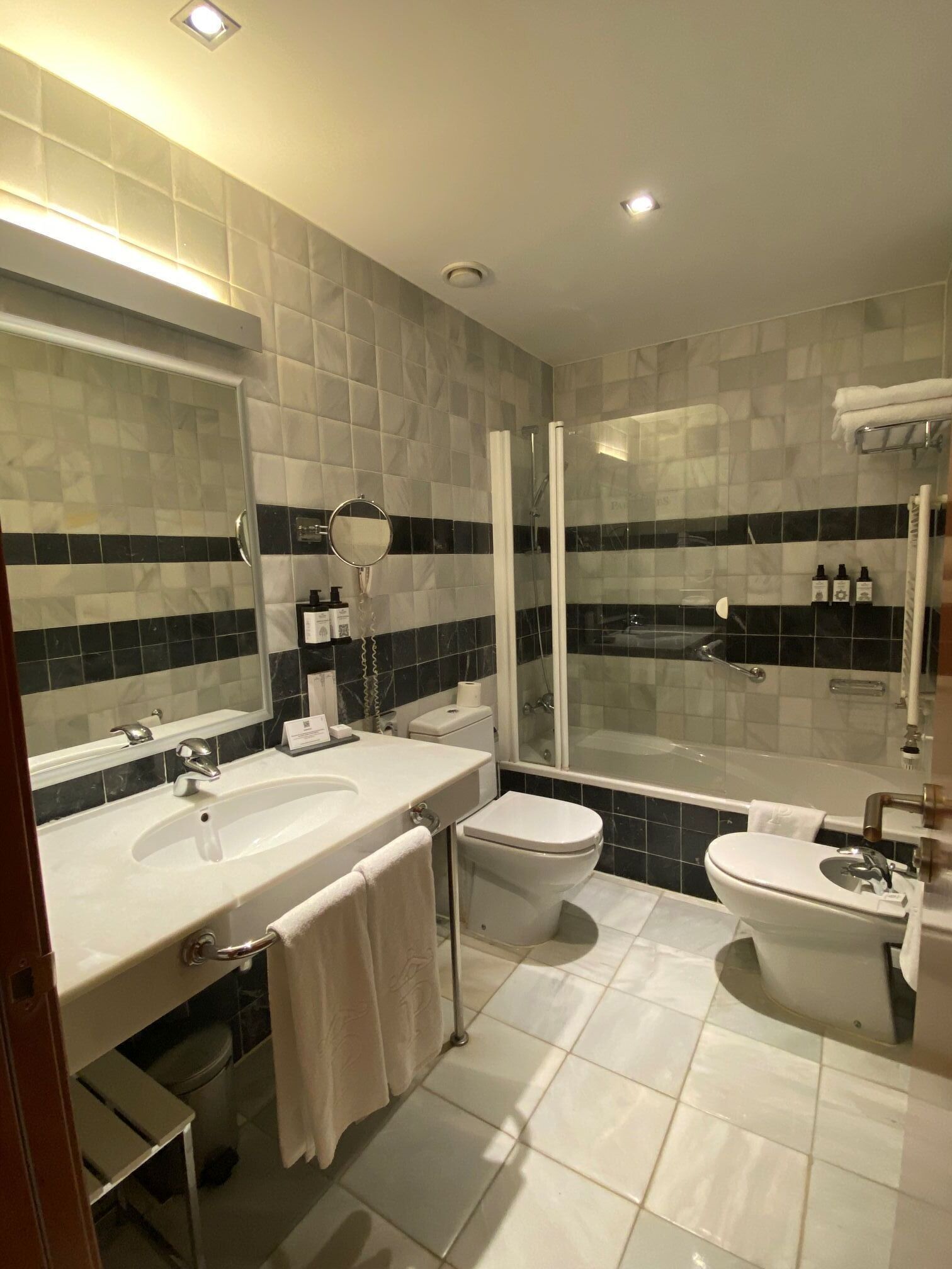 Un baño moderno con un lavamanos grande, inodoro, bidé y zona de ducha con mampara de cristal.