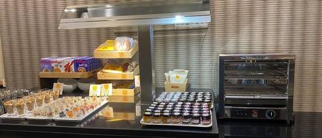 Zona de buffet con diversas opciones de comida, como cereales, frutas y salsas.