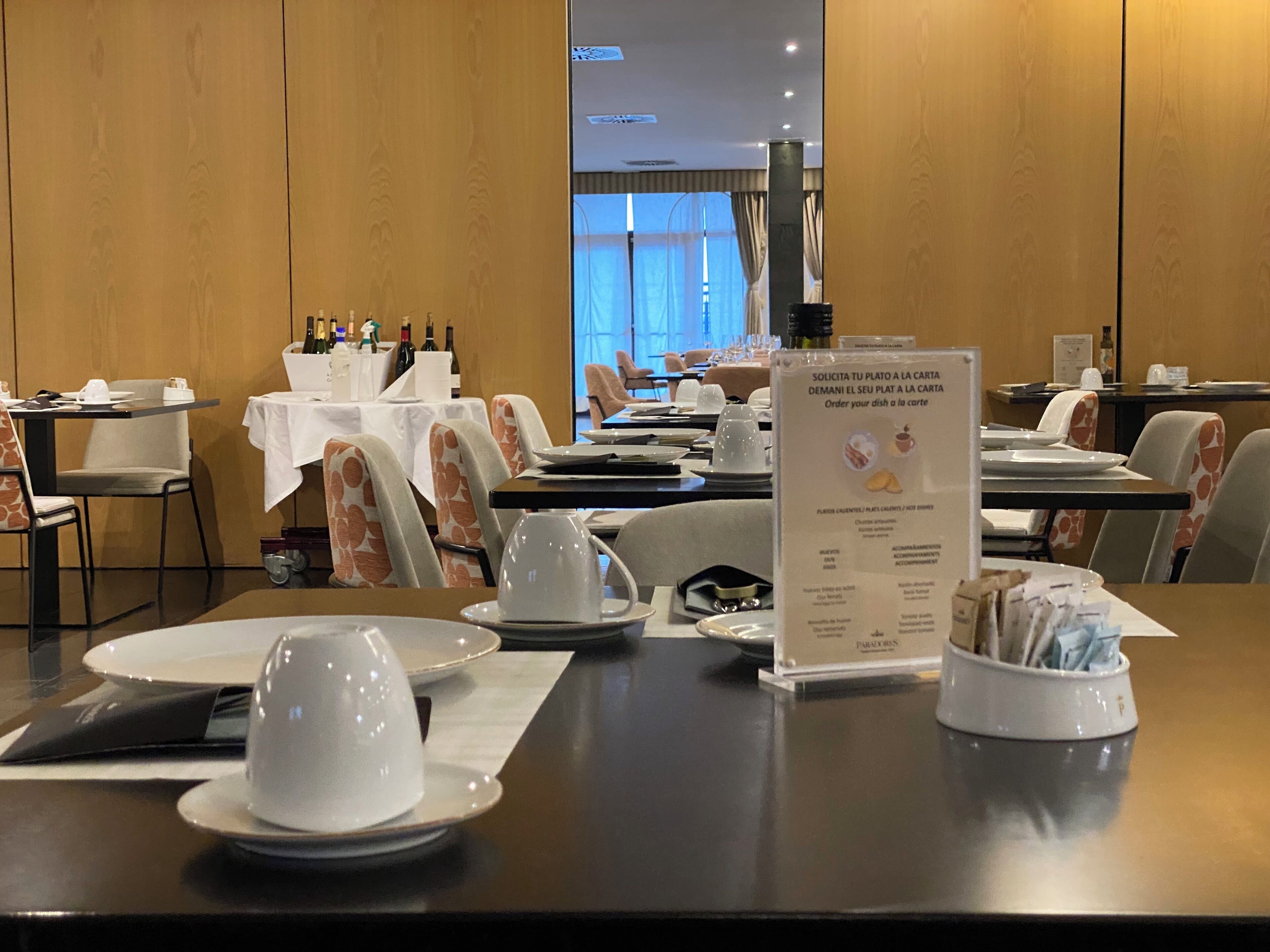 A dining area with tables set for service, a menu stand, and a view of the room.