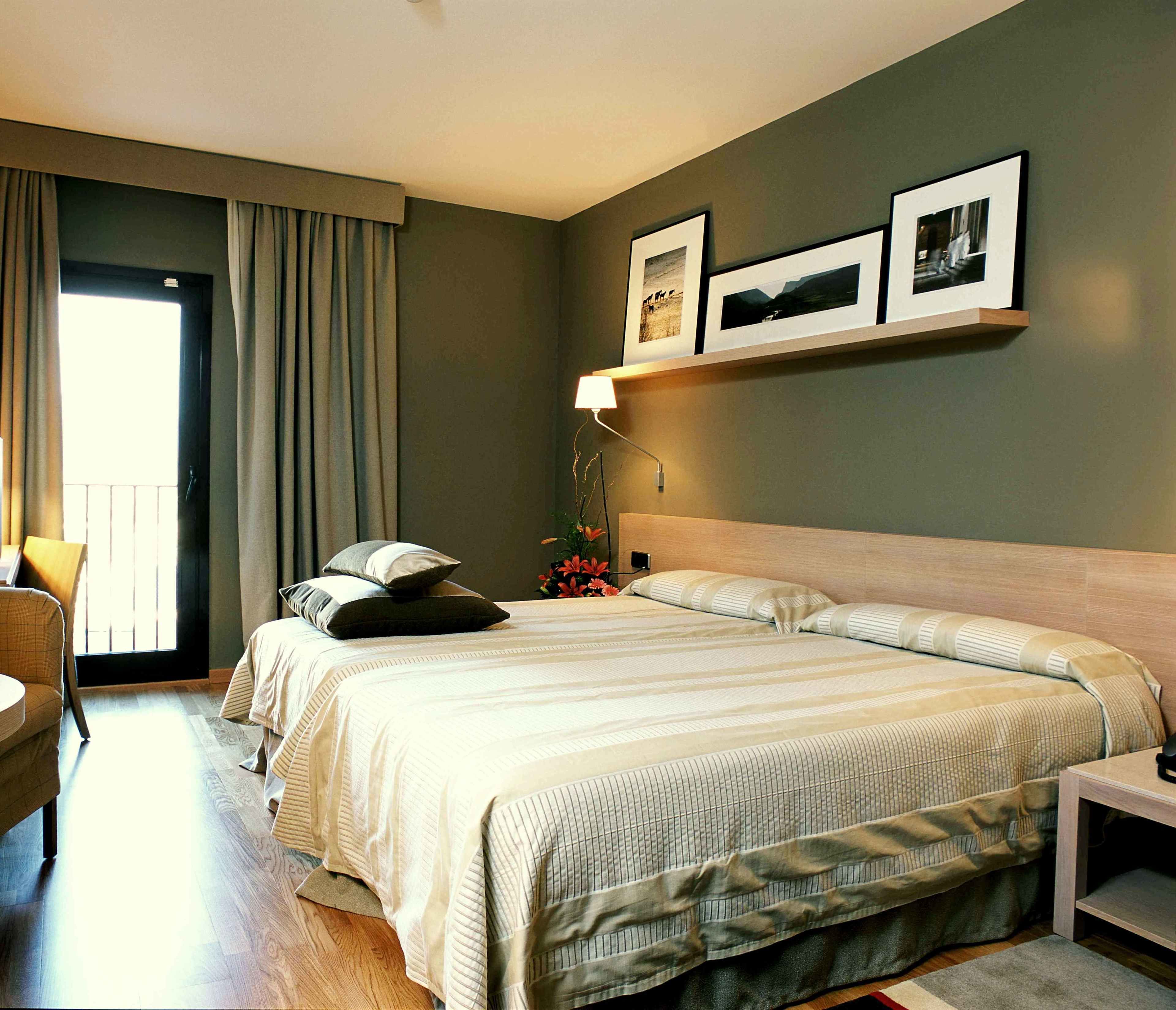 A hotel room with two beds, a desk, a chair, and a window with curtains.