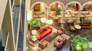 A spacious lobby with a red sofa, multiple chairs, a coffee table, and a potted plant. - Parador de la Seu d'Urgell (La Seu d'Urgell)