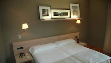 A hotel room with a large bed, bedside lamps, a phone on the nightstand, and framed pictures on the wall.