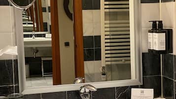 Une salle de bain d’hôtel avec un grand miroir, un lavabo et un porte-serviettes.
