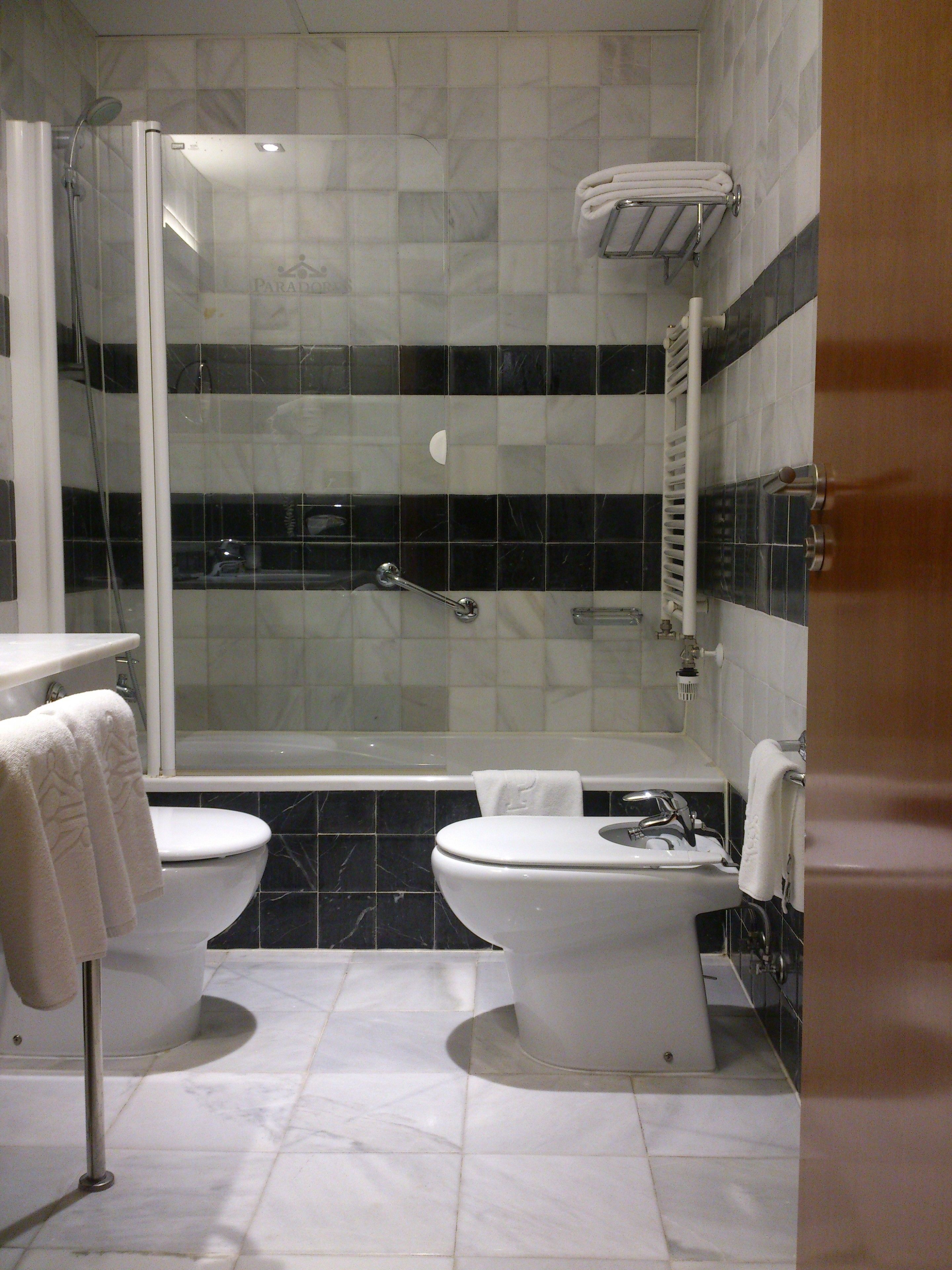 A bathroom with two toilets, a bathtub, and a shower.