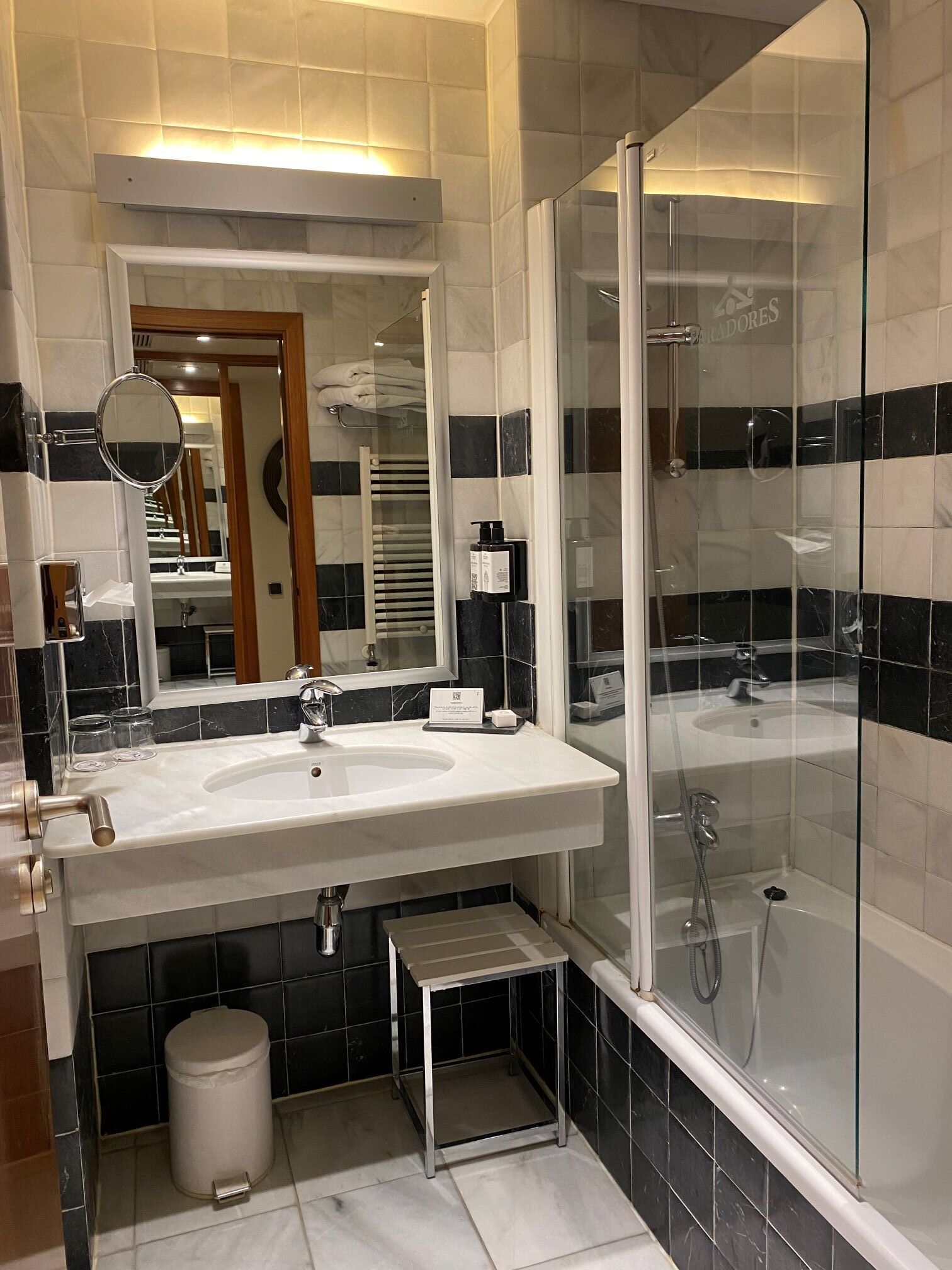 A modern bathroom with a large sink, mirror, and glass-enclosed shower.