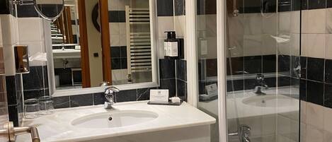 A modern bathroom with a large sink, mirror, and glass-enclosed shower.