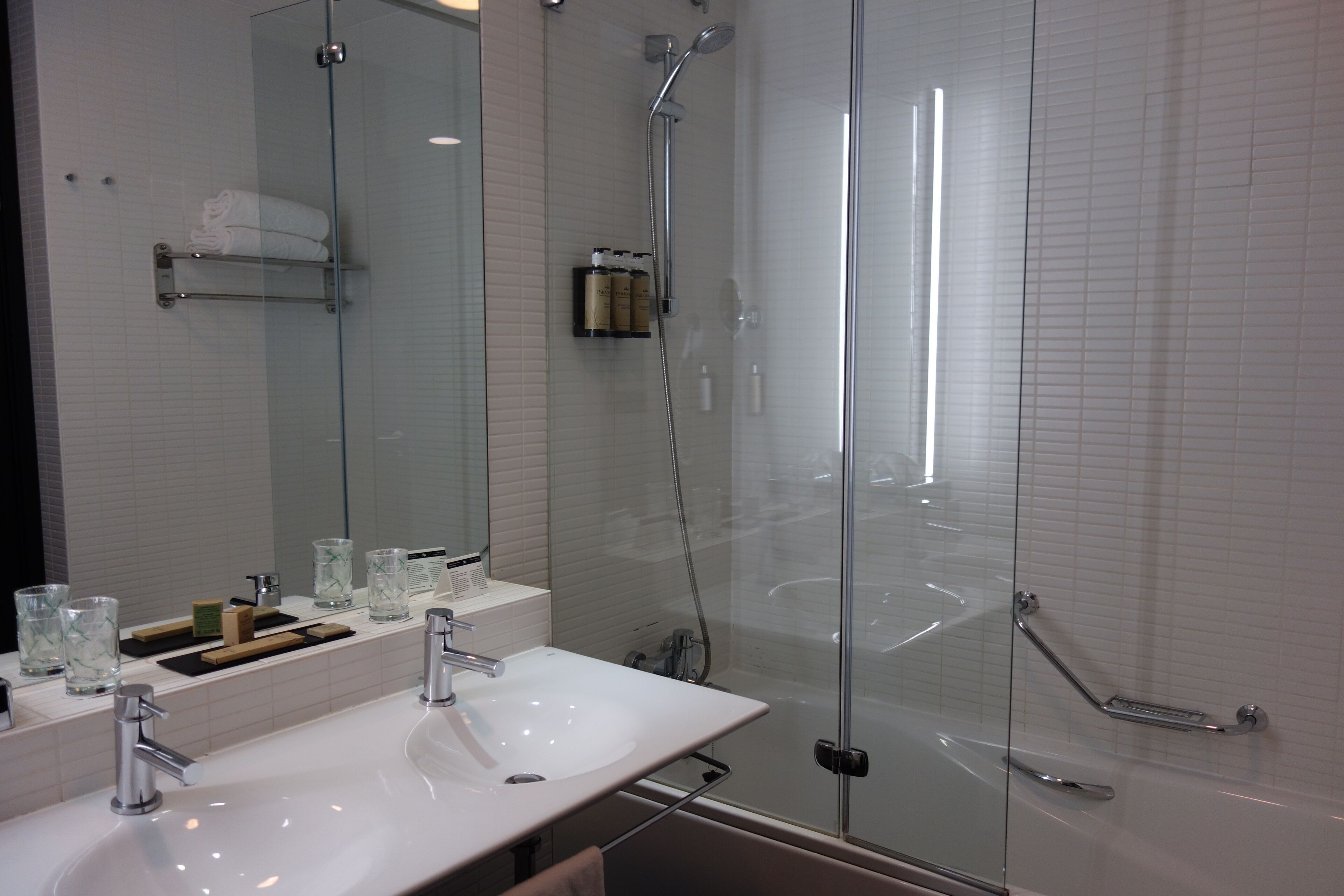 Un baño moderno con ducha de vidrio, lavamanos blanco y espejo grande.