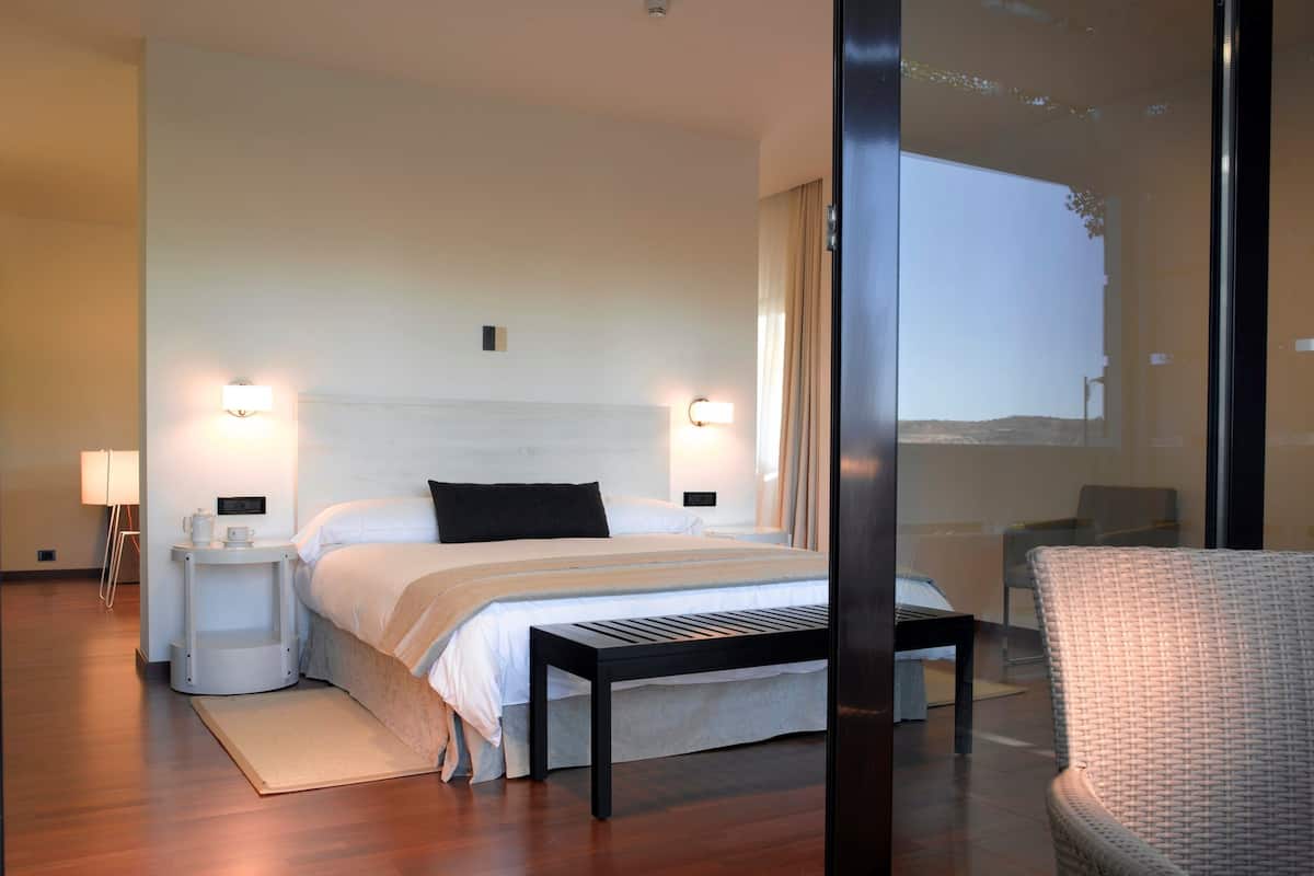 Une chambre d’hôtel moderne avec un grand lit, des tables de chevet, une petite table et une chaise.