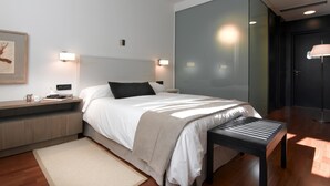 Een moderne slaapkamer met een groot bed, nachtkastjes, een bankje en een vloerkleed.