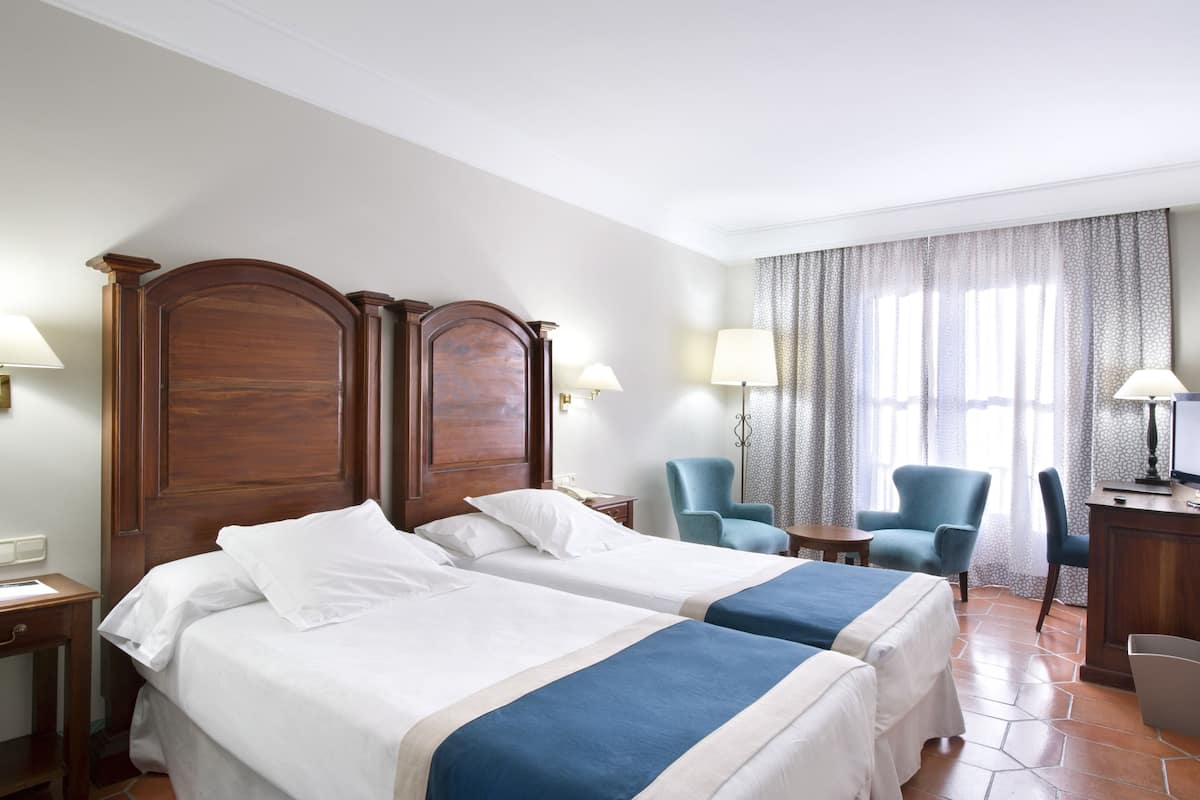 Ein Hotelzimmer mit zwei Betten, einem Schreibtisch, einem Stuhl und einem Fernseher.