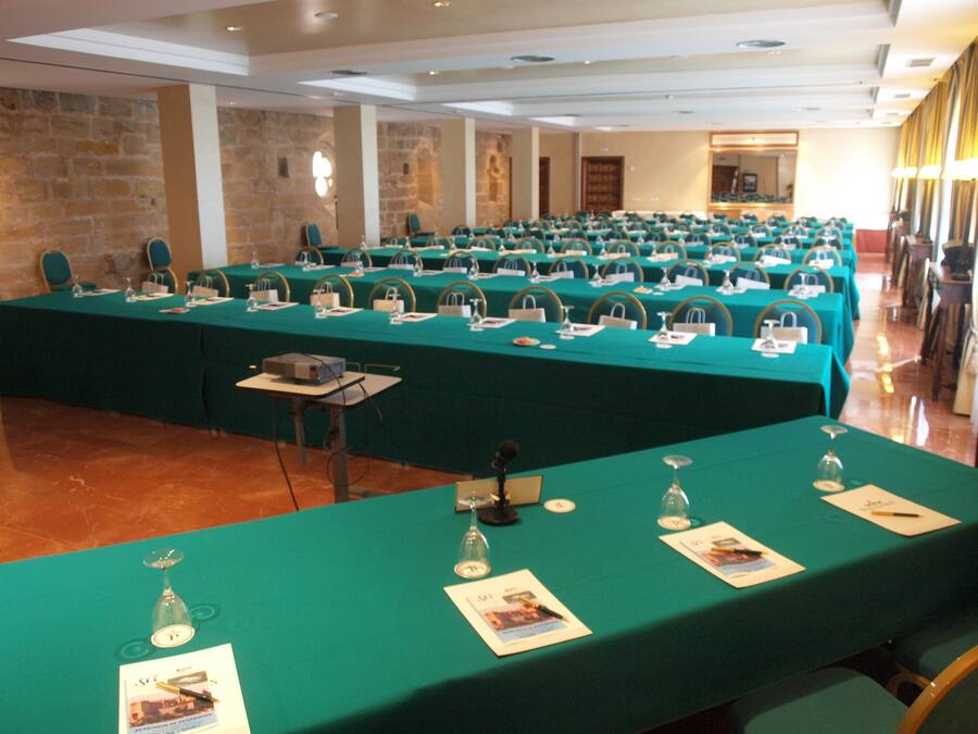 Une salle de conférence avec des rangées de tables, chacune étant équipée de plaques nominatives, de microphones et de verres.