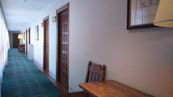 A hallway with wooden doors, a bench, and a table.