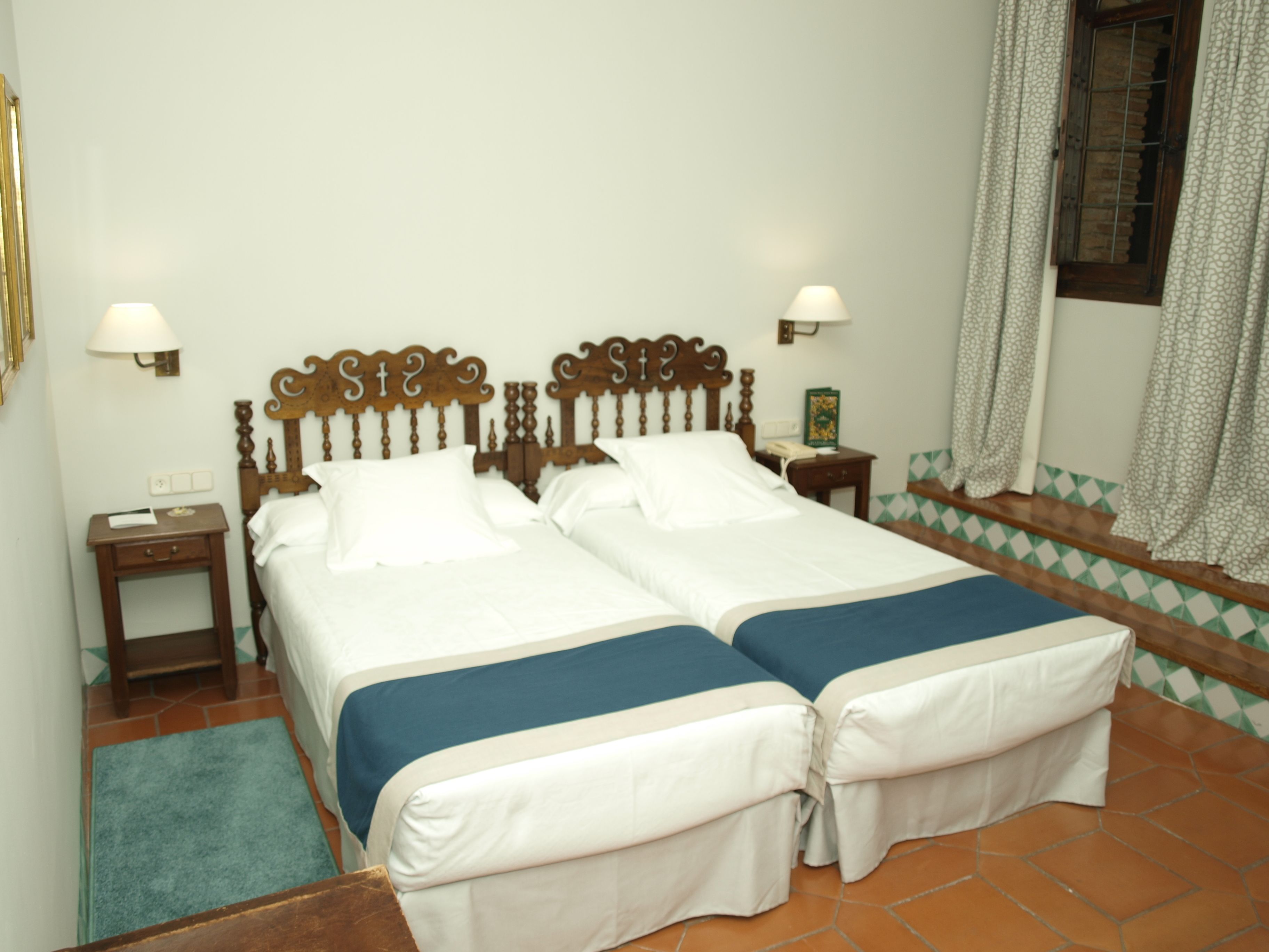 Una cama doble con cabecera de madera, dos mesitas de noche y una mesita auxiliar.